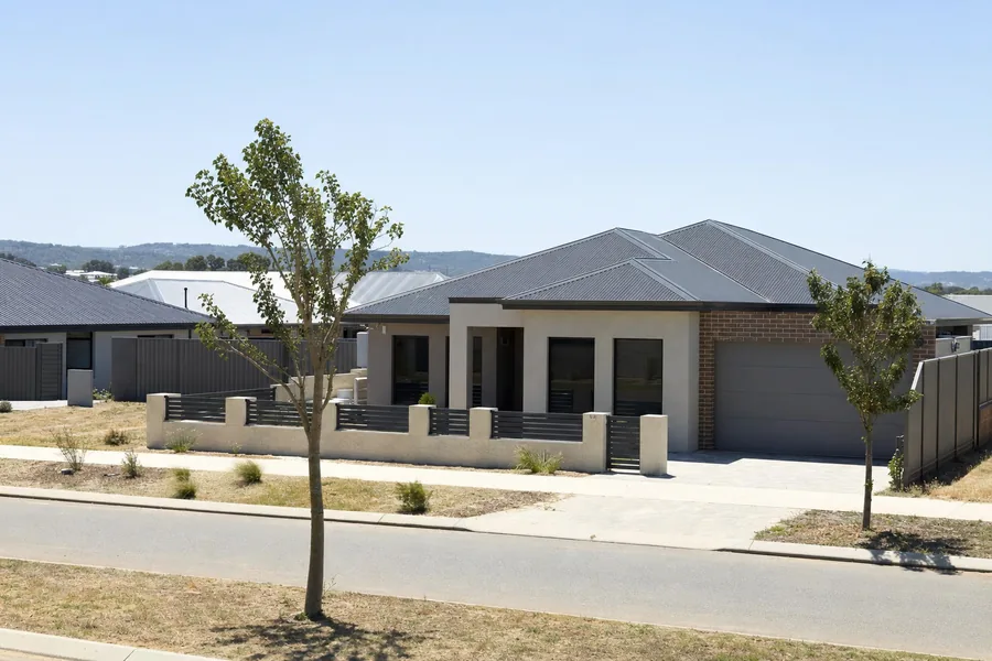 A flat block in a newer estate south of the river, mixed sand and clay ground, rendered and brick home with a Colorbond roof, the Darling scarp on the horizon — illustrative example